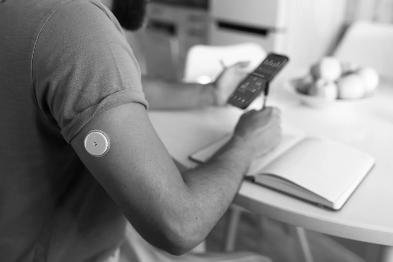 Man with a glucose sensor on his arm taking notes on his meals